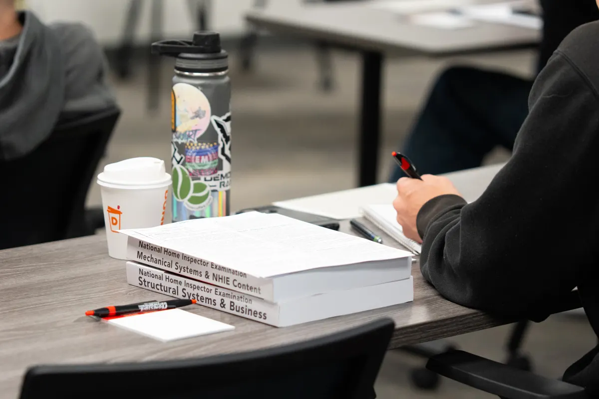 NHIE exam prep books on a student's desk