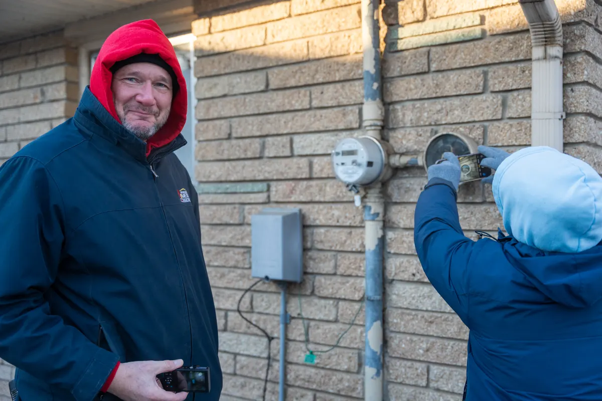Student checking an electric meter outside a home during field training