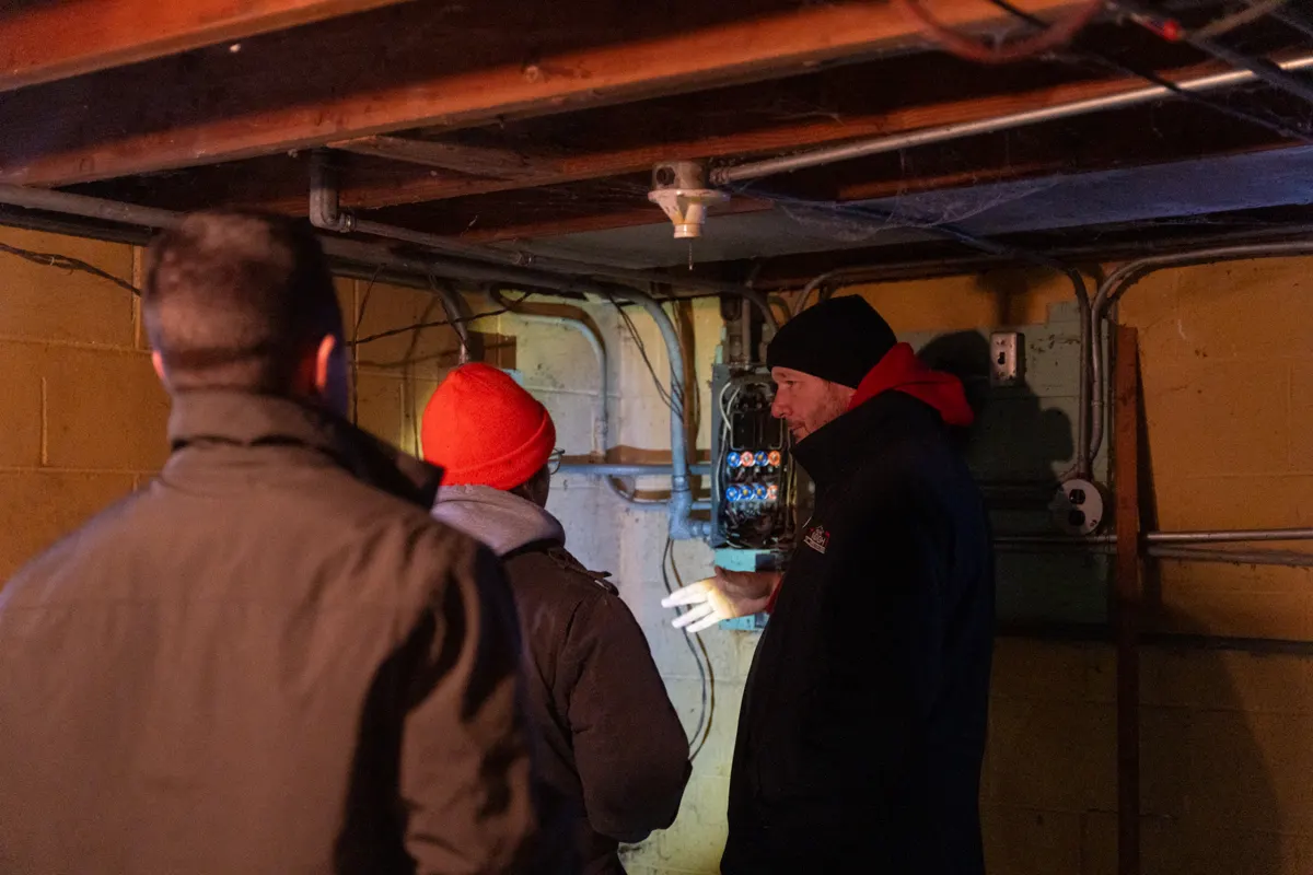 Students examining an electrical panel in a basement during field training