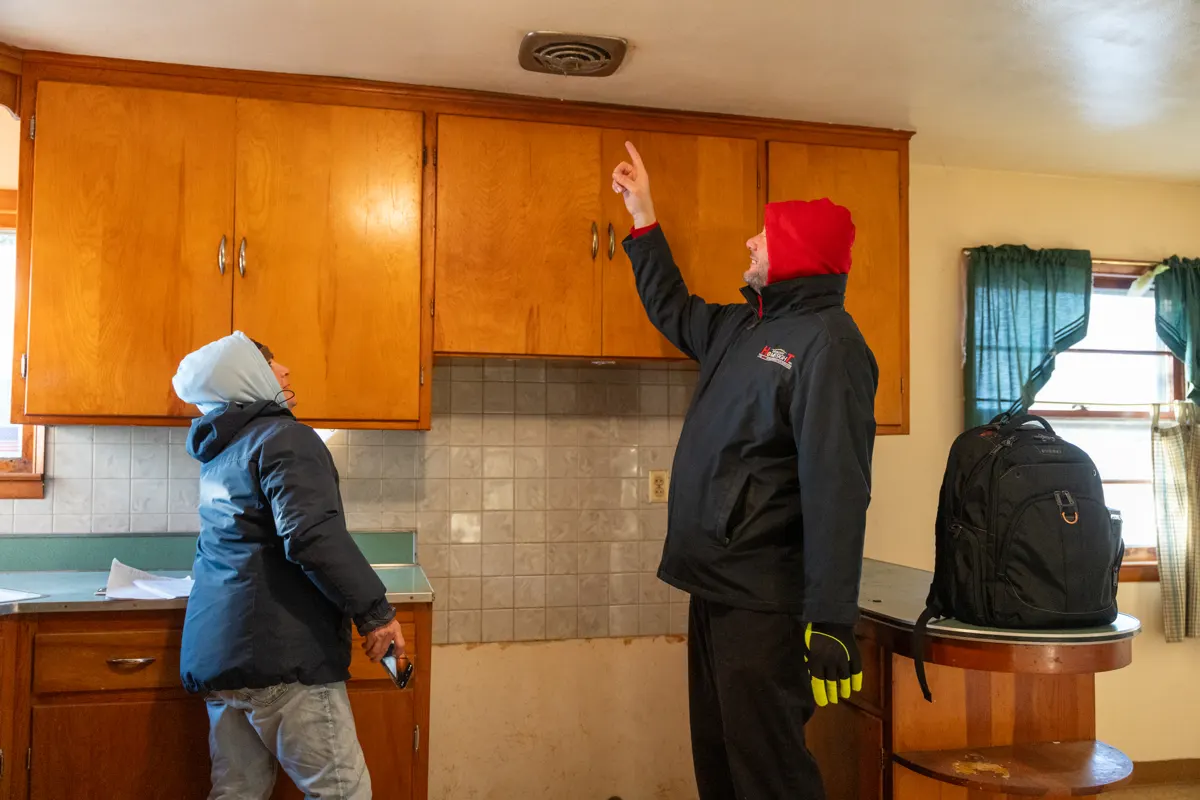 Instructor pointing out kitchen conditions to a student during an on-site inspection